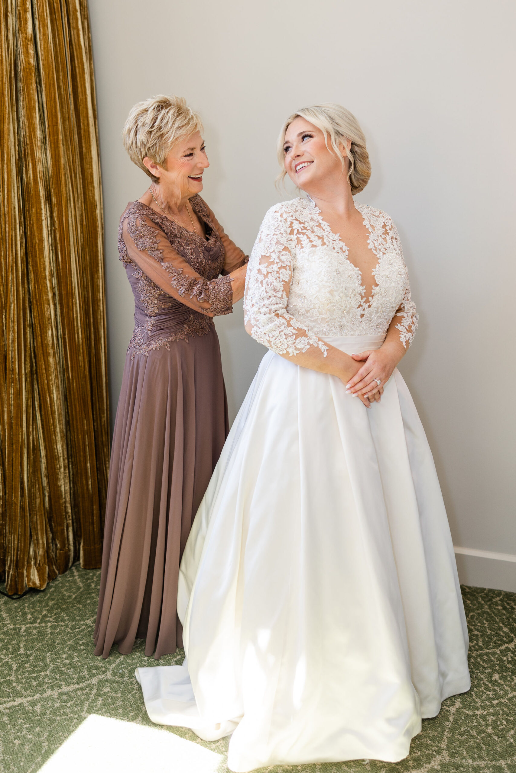 The mother of the bride helps her daughter into her Alabama wedding dress.