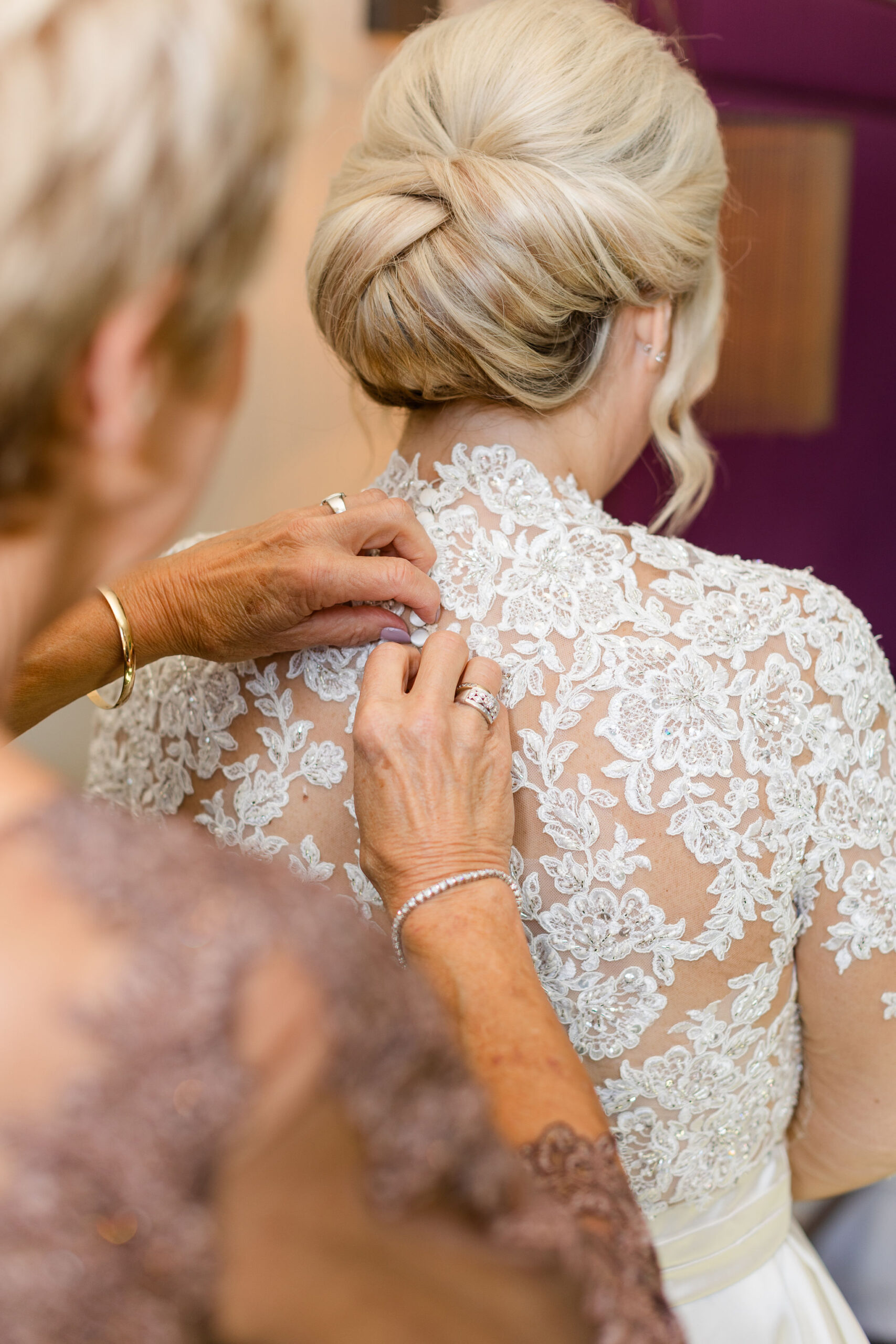 The mother of the bride buttons her daughter's bridal gown at Grand Bohemian Hotel Mountain Brook.