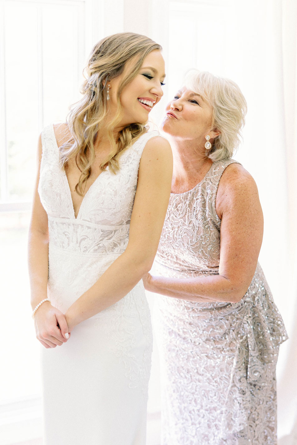 The mother of the bride helps her daughter into her wedding dress.