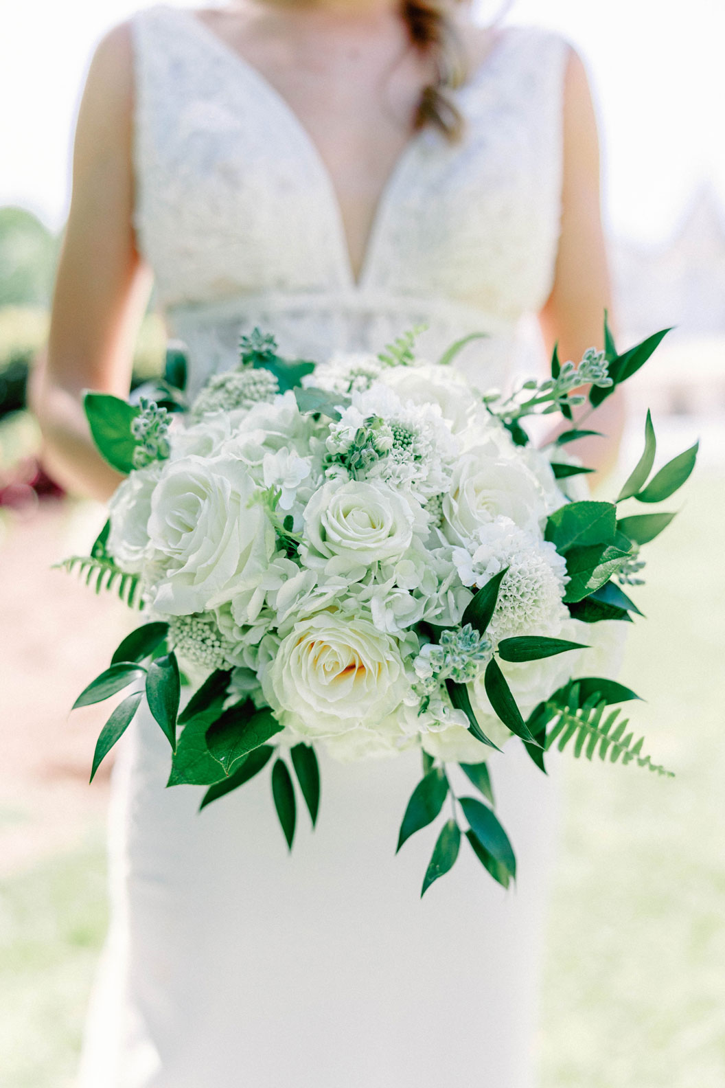 The bride holds her floral bouquet by The Sonnet House.