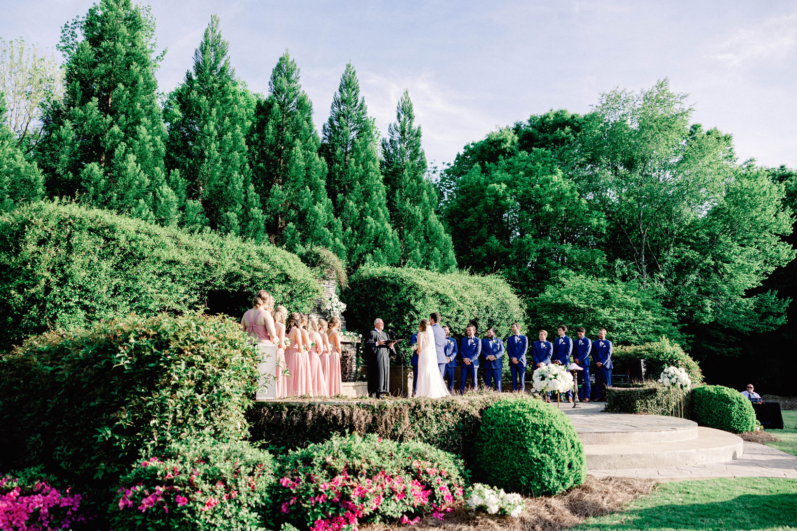 The bride and groom begin their wedding ceremony in front of beautiful landscaping at The Sonnet House.