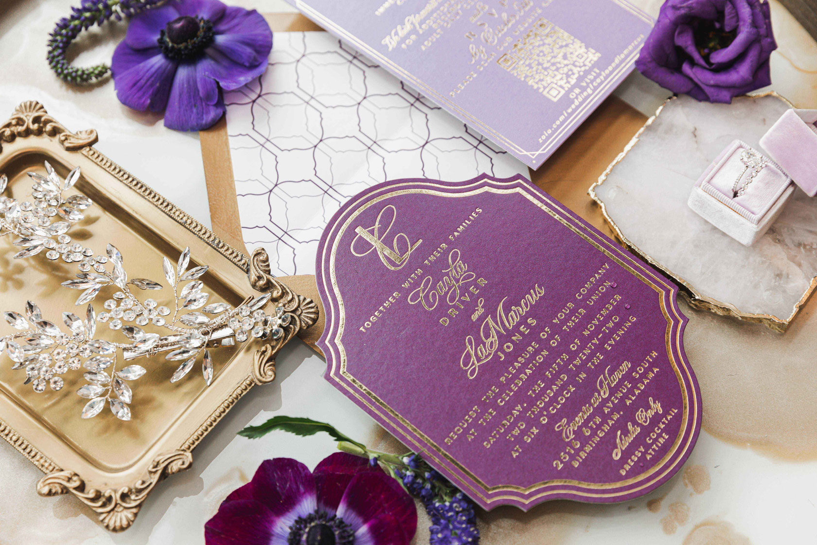 The purple wedding invitations are styled in a lay flat with the bride's accessories.