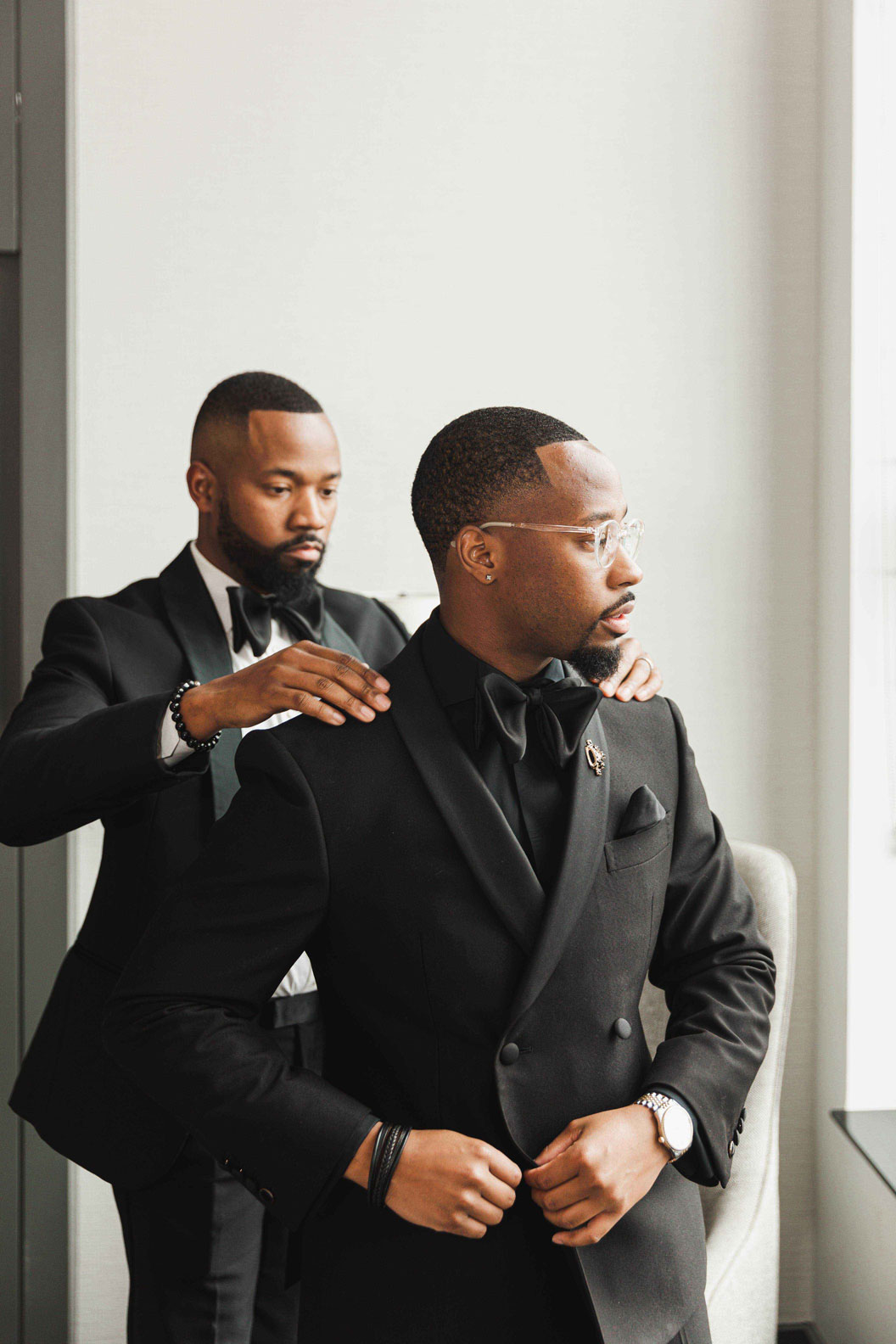 The groomsman helps the groom put on his tuxedo for his Birmingham weddings