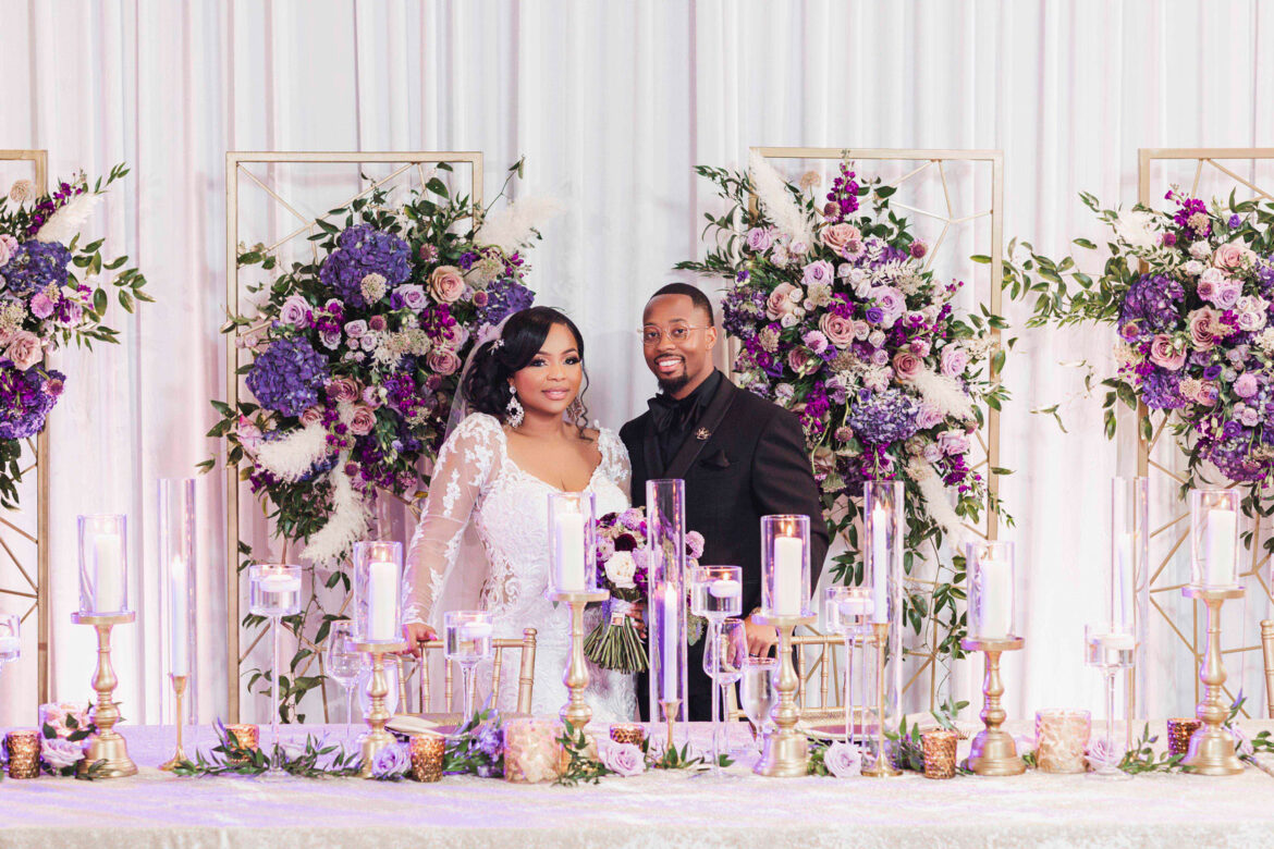 The couple stands behind the head table of their wedding reception at Haven in Birmingham.