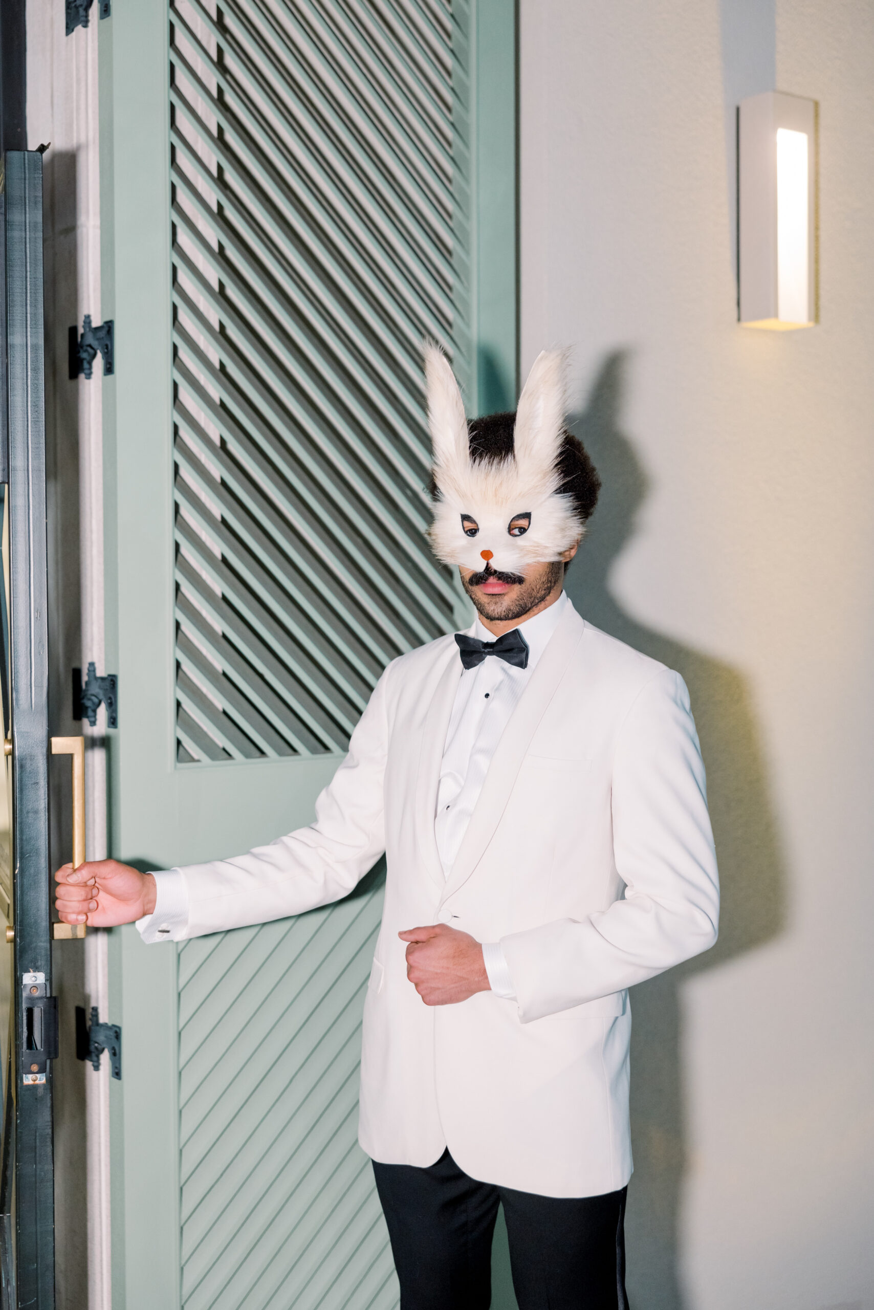 A dapper man in a bunny mask and white tuxedo opens the door for the Alabama Weddings party in Birmingham.