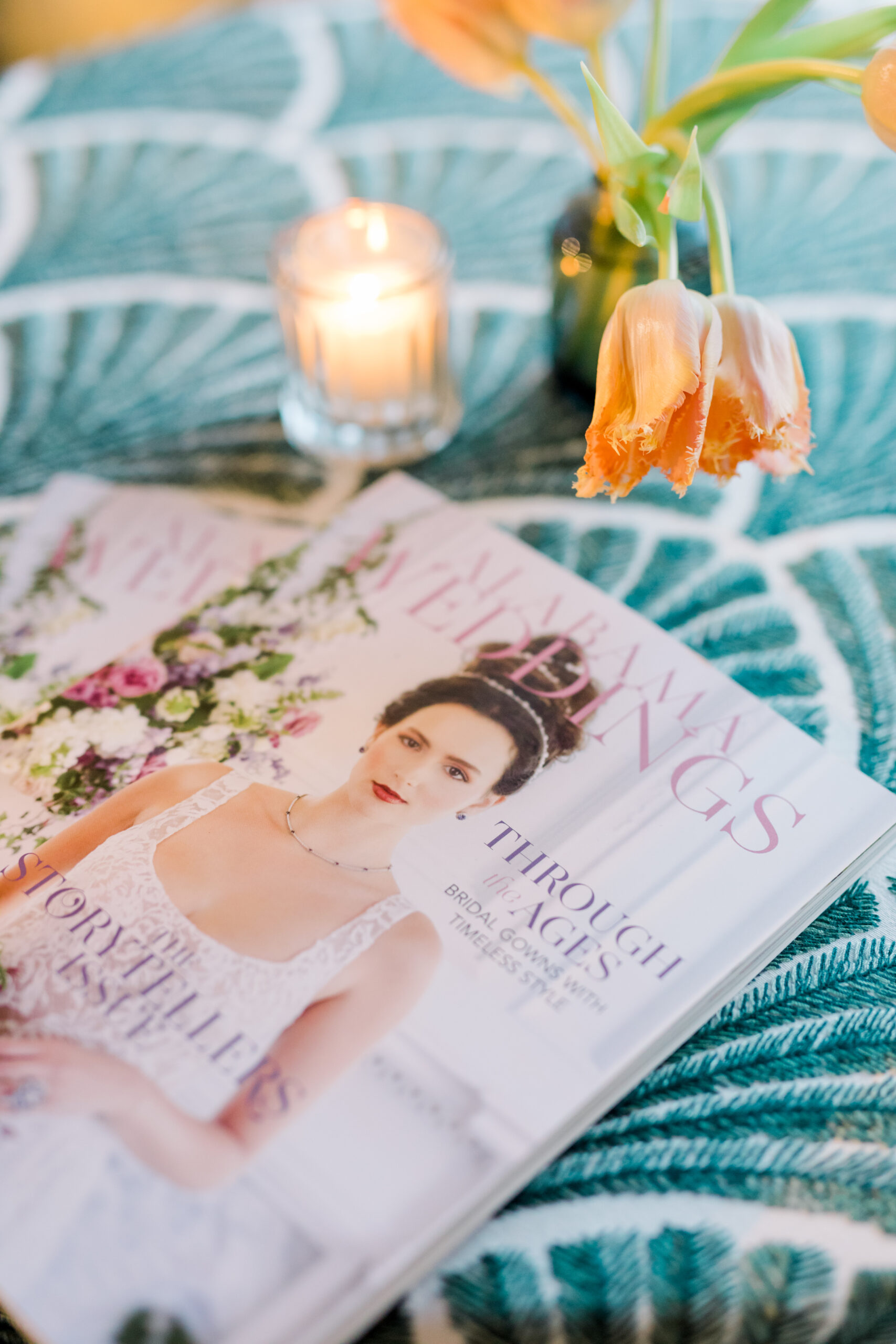 Copies of Alabama Weddings 2023, The Storytellers Issue, are placed on a cocktail table next to tulips.