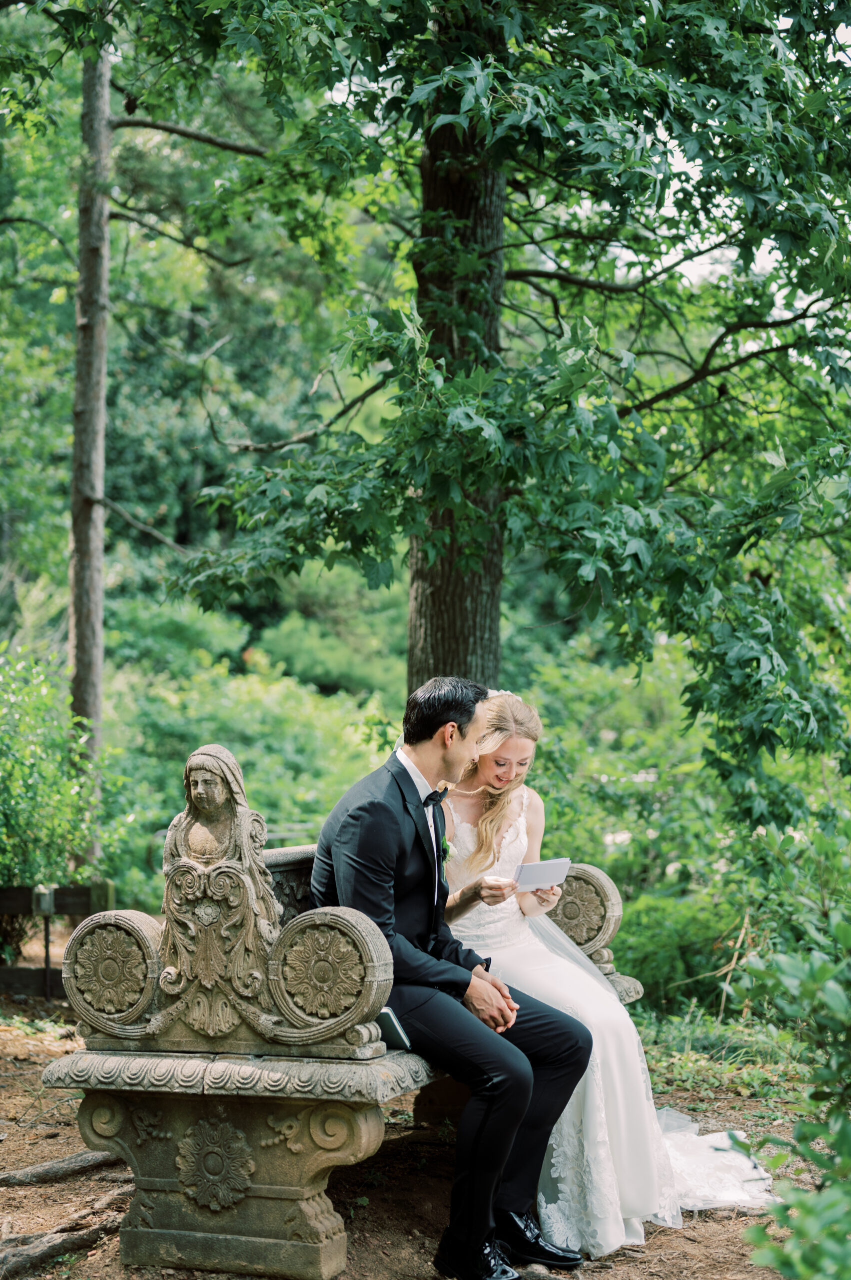 The Southern bride reads a letter from the groom on the garden bench.