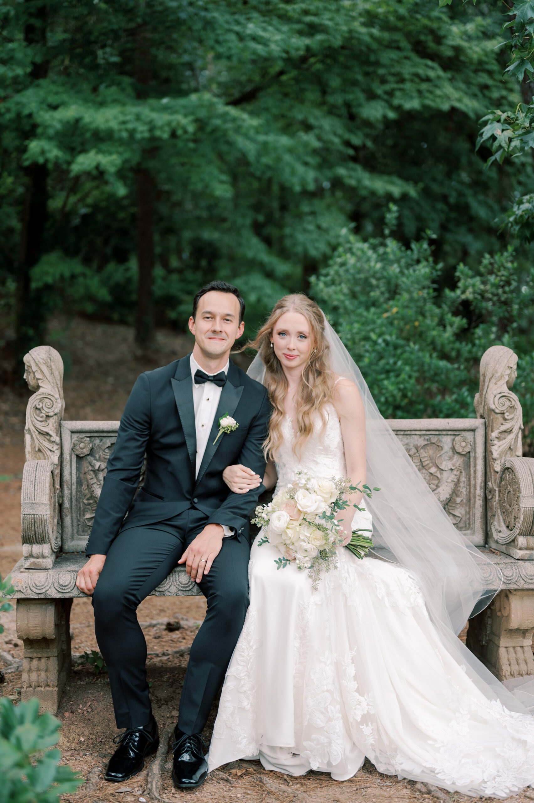 The Southern bride and groom sit together on the garden bench.