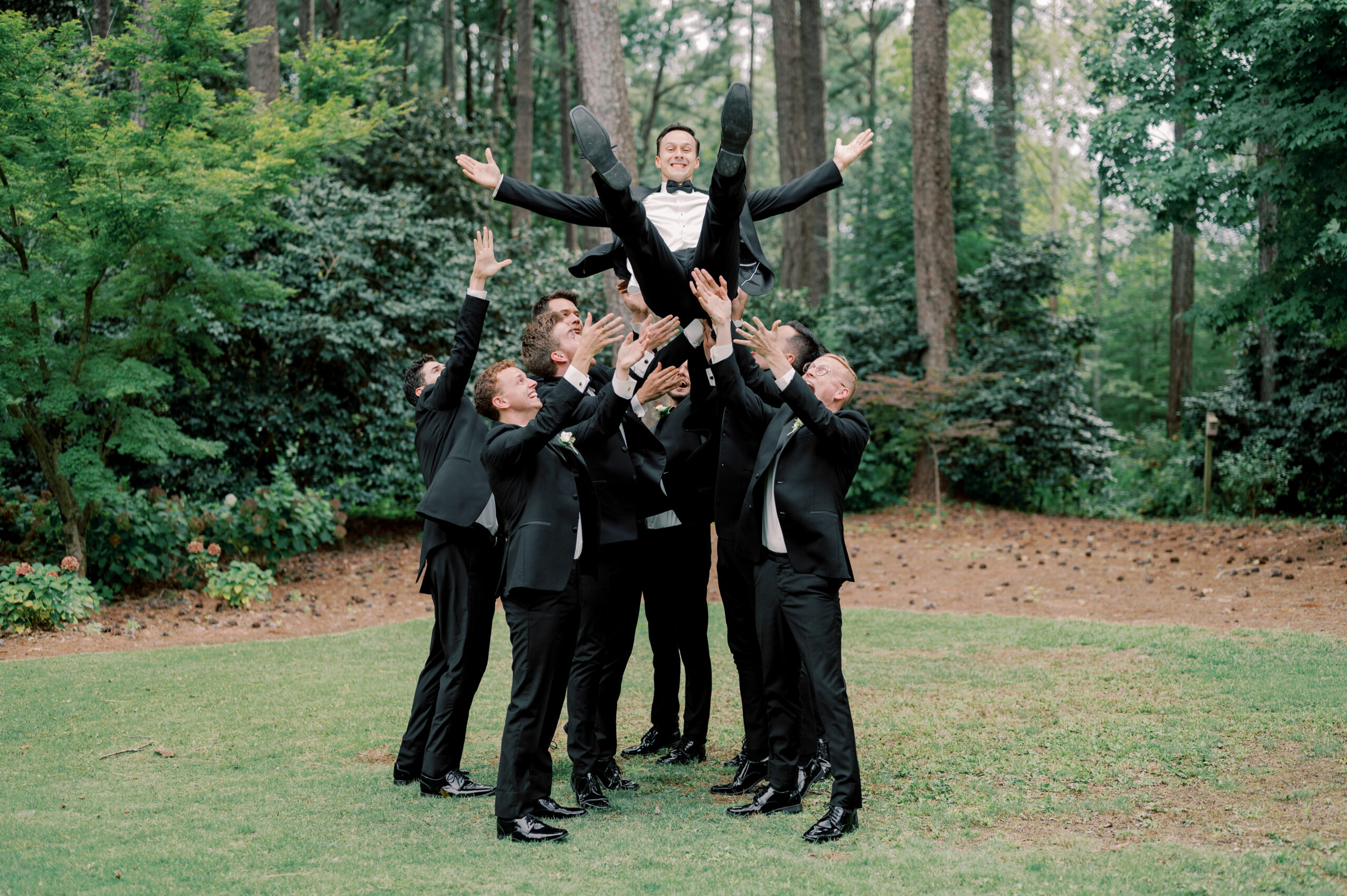 The groomsmen lift the groom and laugh at Aldridge Garden.