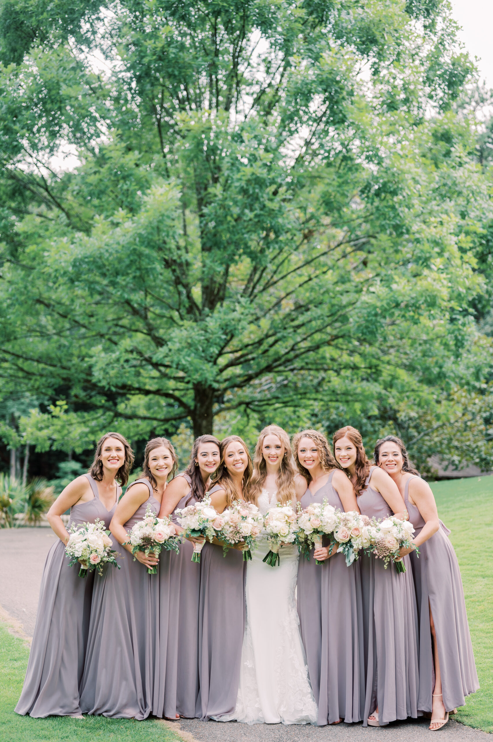 The bridesmaids smile with the Southern bride in the garden.