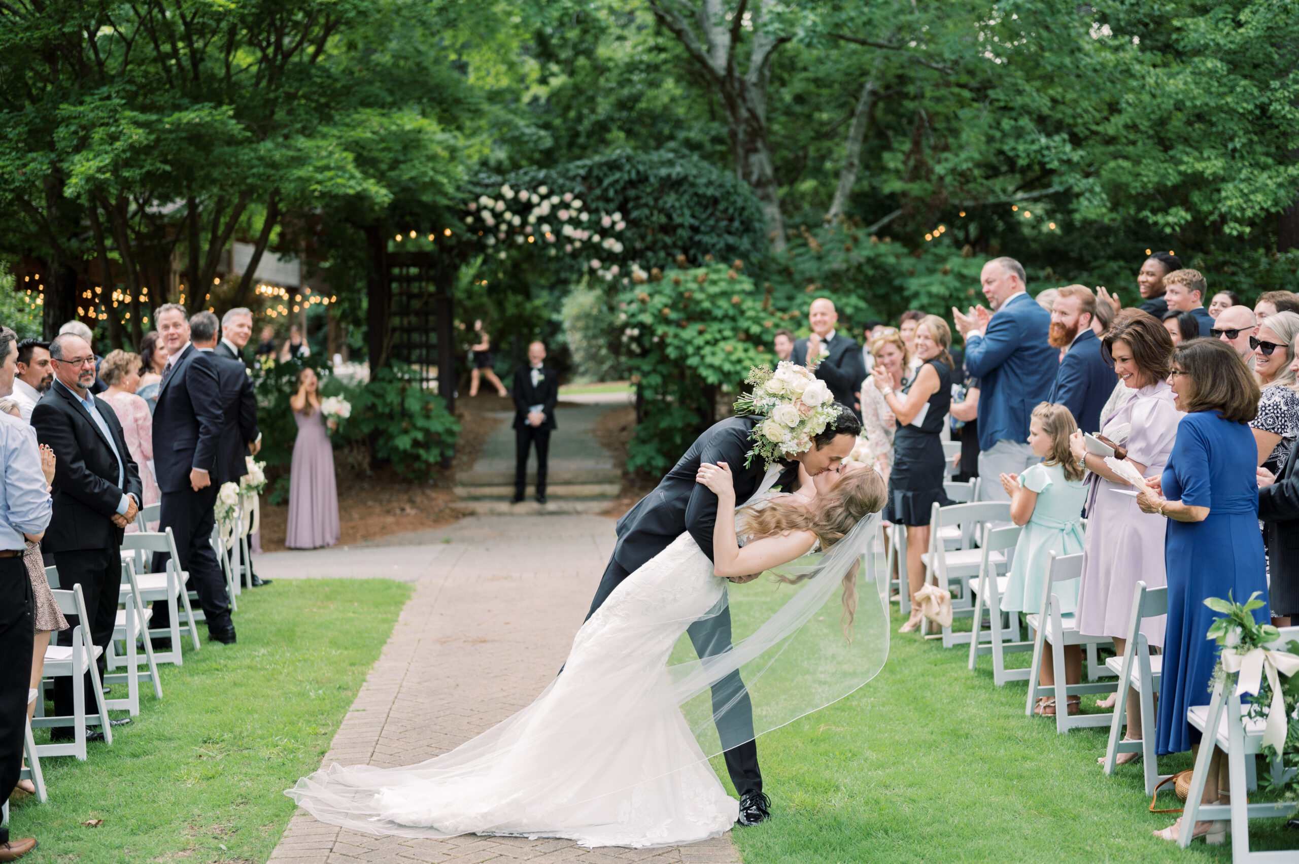 The groom kisses the bride as they exit their garden wedding ceremony.