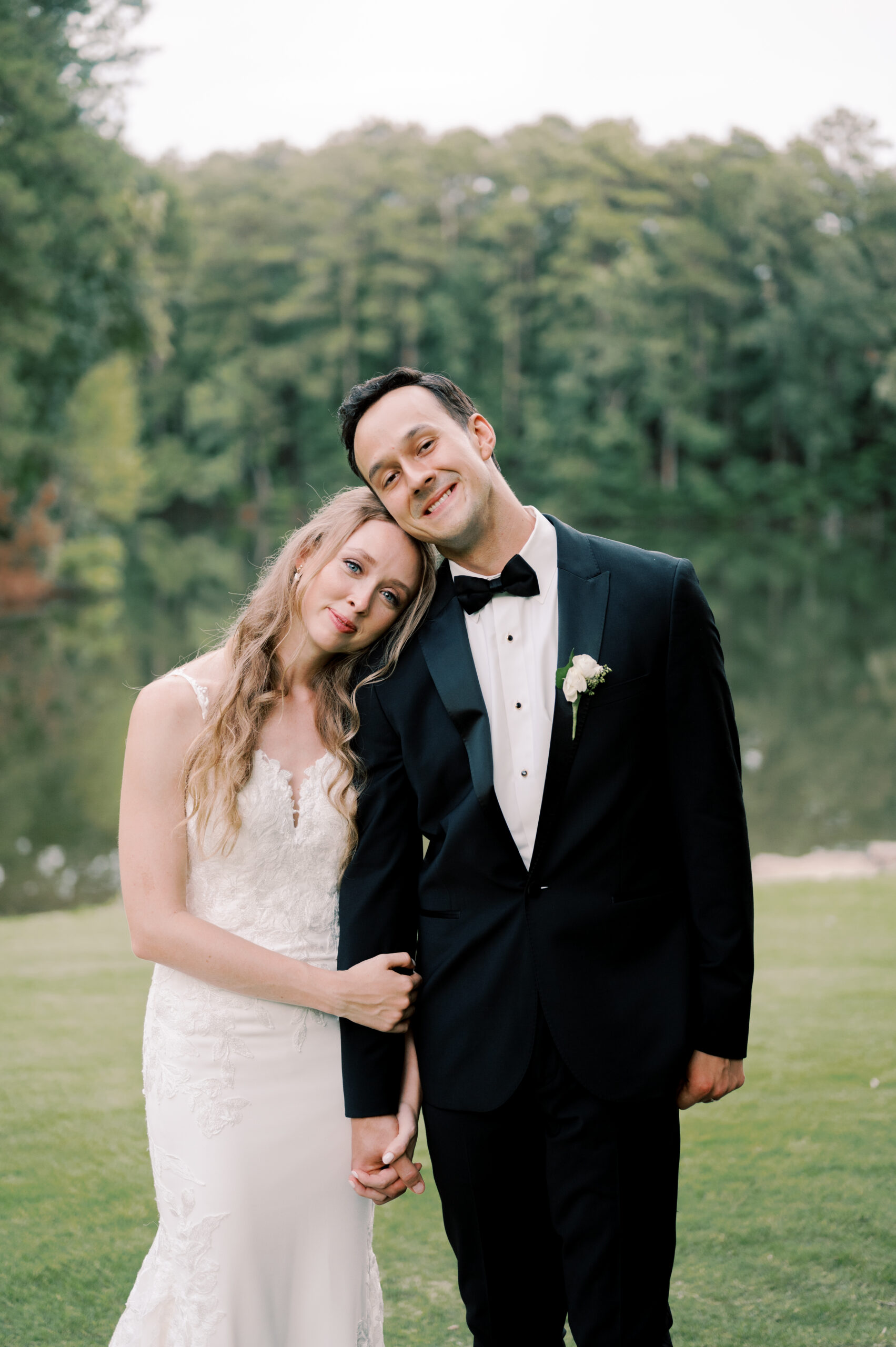 The bride leans her head on the groom's shoulder in the garden.