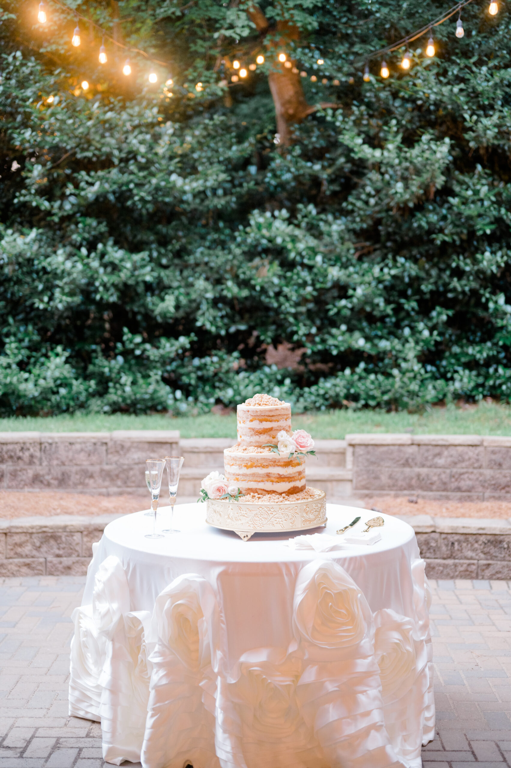 The wedding cake by Daughter's Baking in Mountain Brook is displayed in the garden.