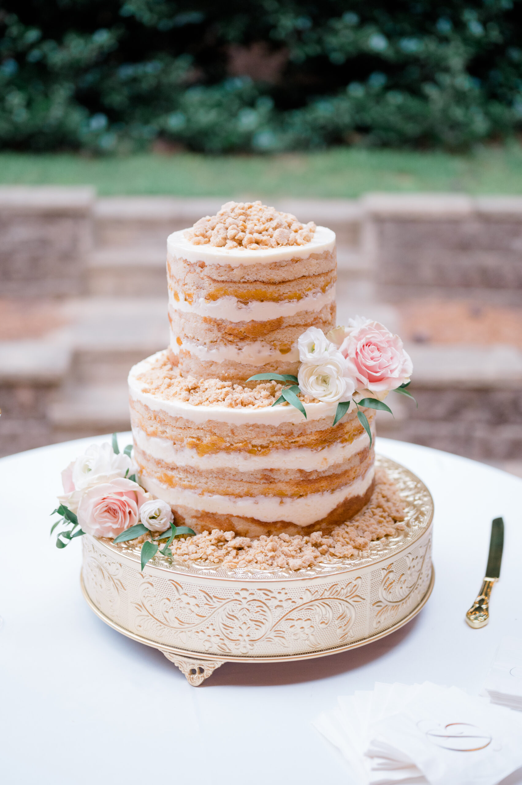 This naked wedding cake by Daughter's Baking is displayed on a gold cake plateau.