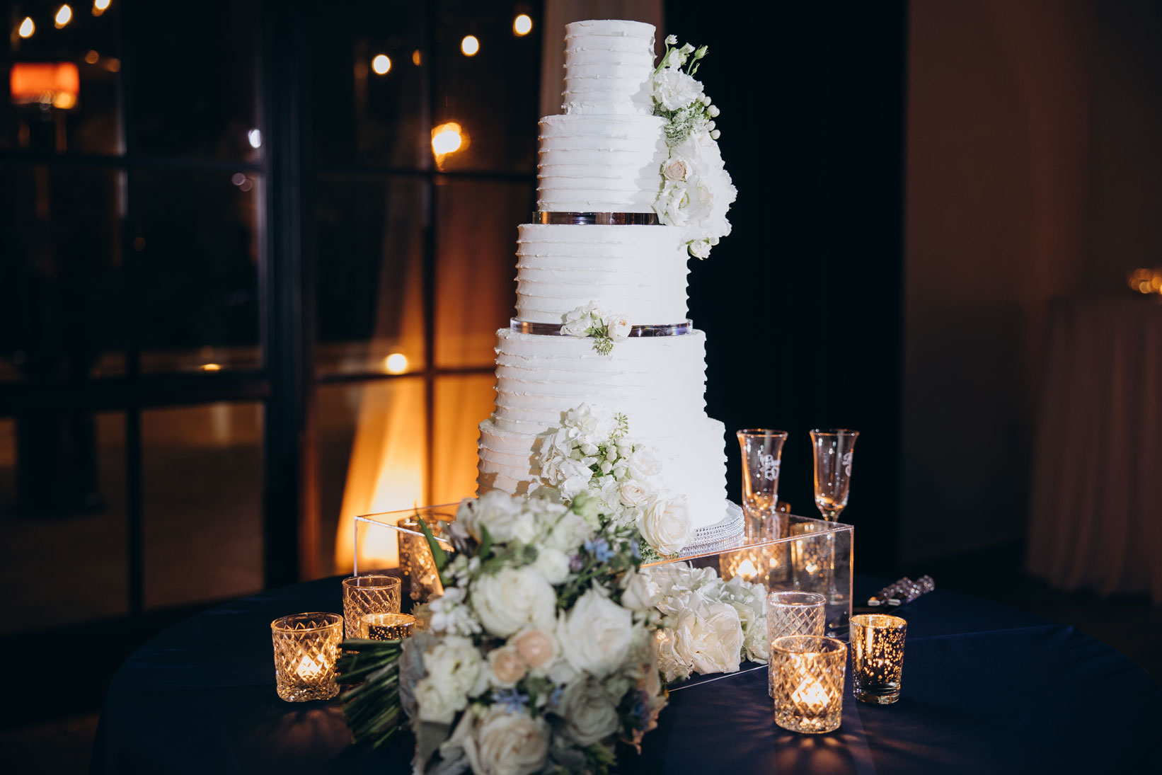 The wedding cake from Cakes by Kim is set on an acrylic stand and decorated with fresh flowers for this wedding reception in Birmingham.