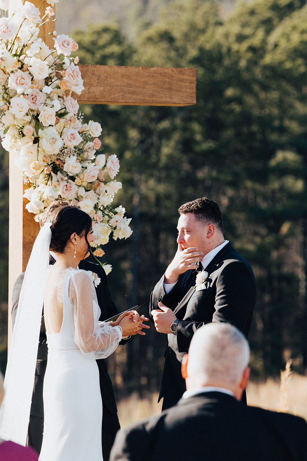 The groom tears up in front of the cross decorated in flowers for the wedding reception in Alabama.