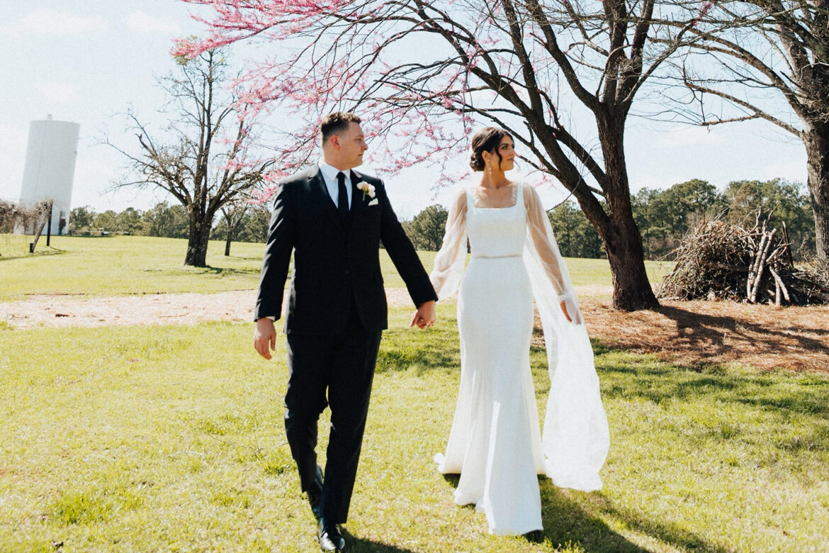 The bride and groom walk together through the park in Alabama.