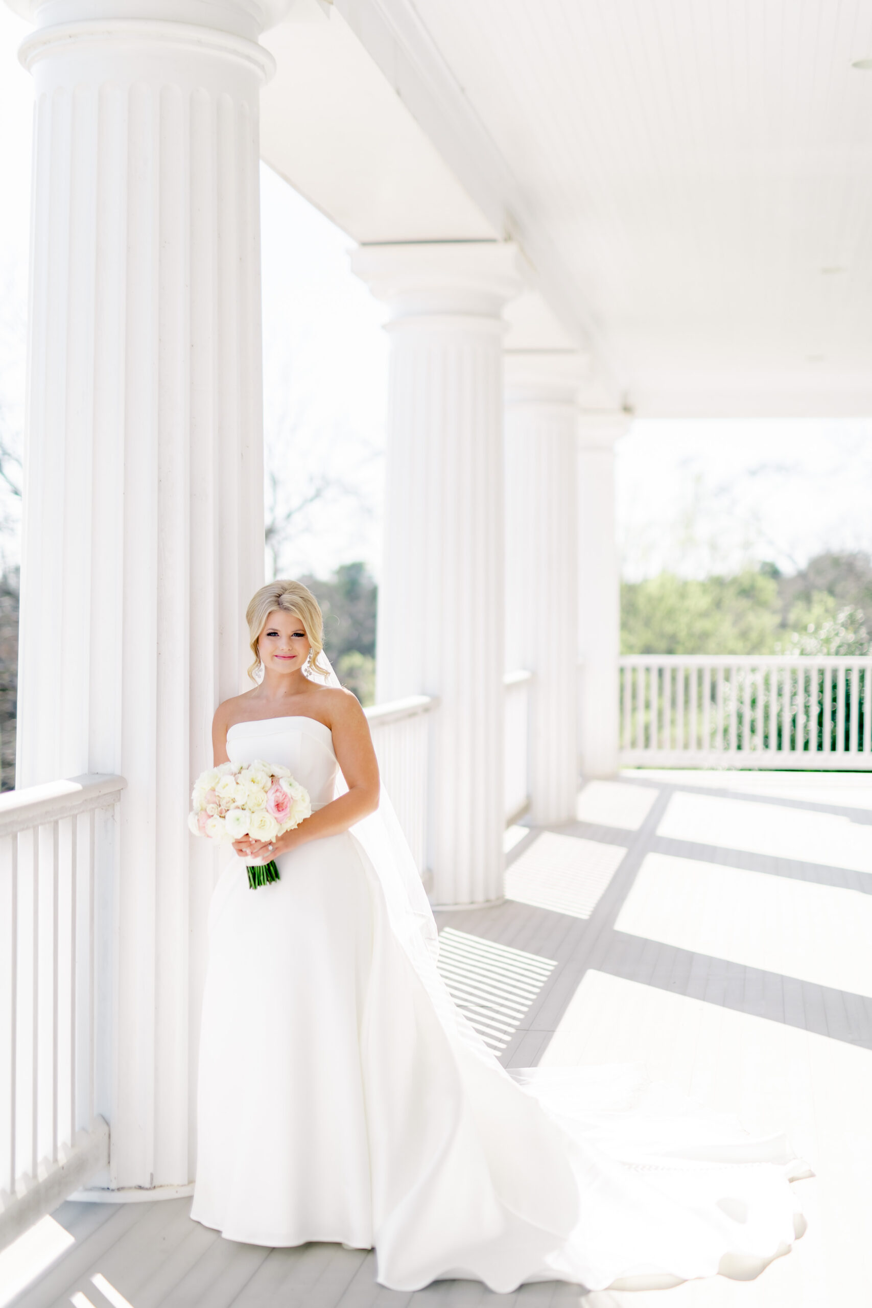 The bride leans against a column on the porch at Marsgate wedding venue in Alabama.