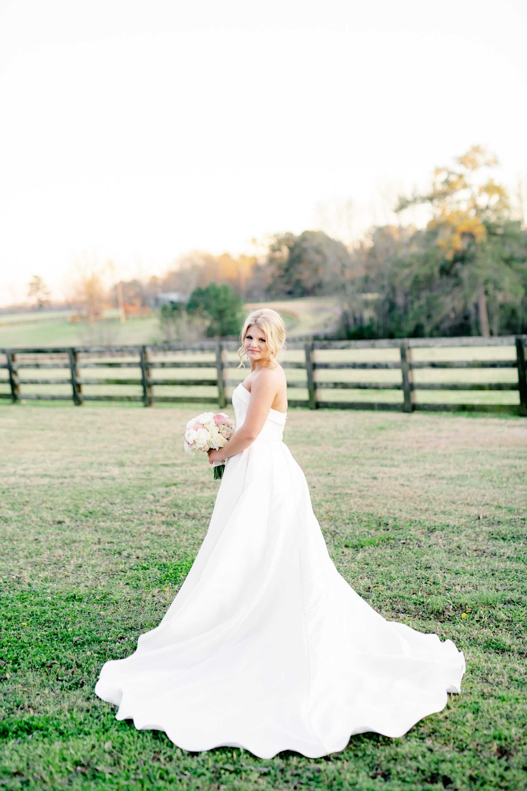 The bride poses with her bouquet in a field at Marsgate.