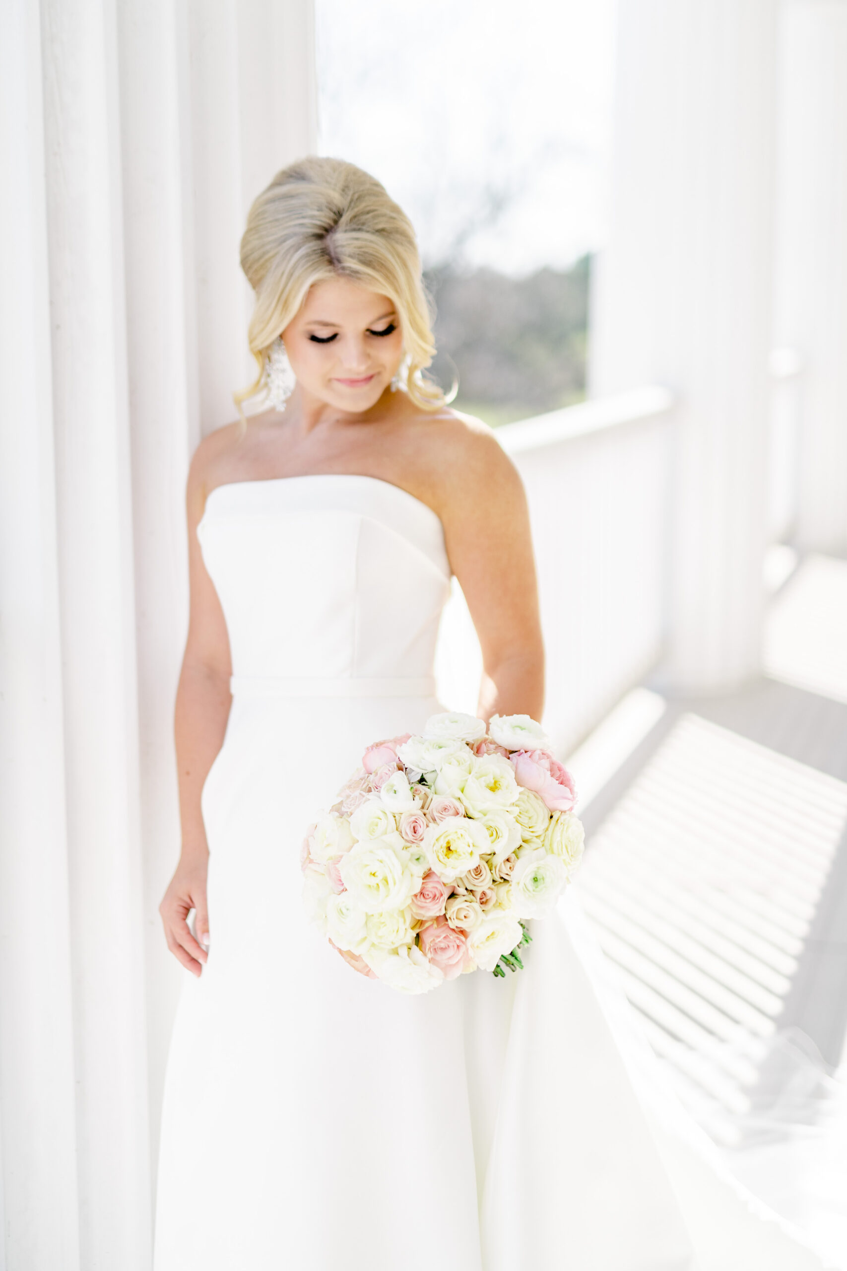 The bride poses with her bouquet on the porch at Marsgate.