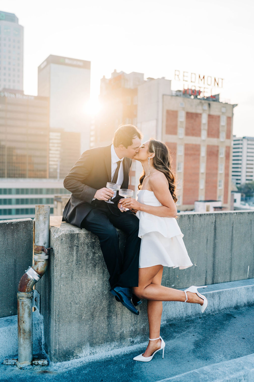 The bride and groom kiss as they sip champagne to celebrate their engagement in downtown Birmingham, Alabama.