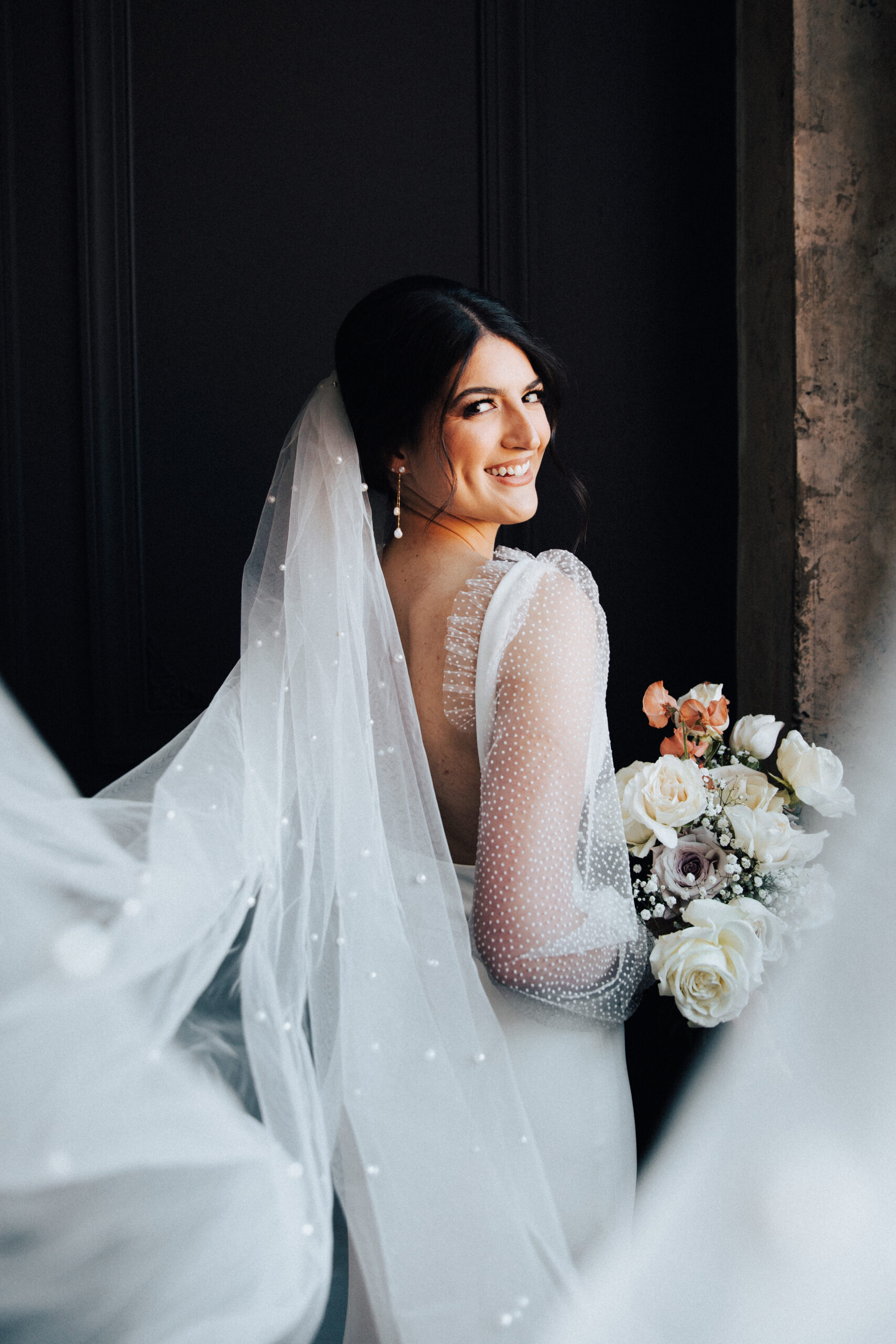 The bride poses with her bouquet in her wedding dress and pearled veil from Birch on Main in Huntsville, Alabama.