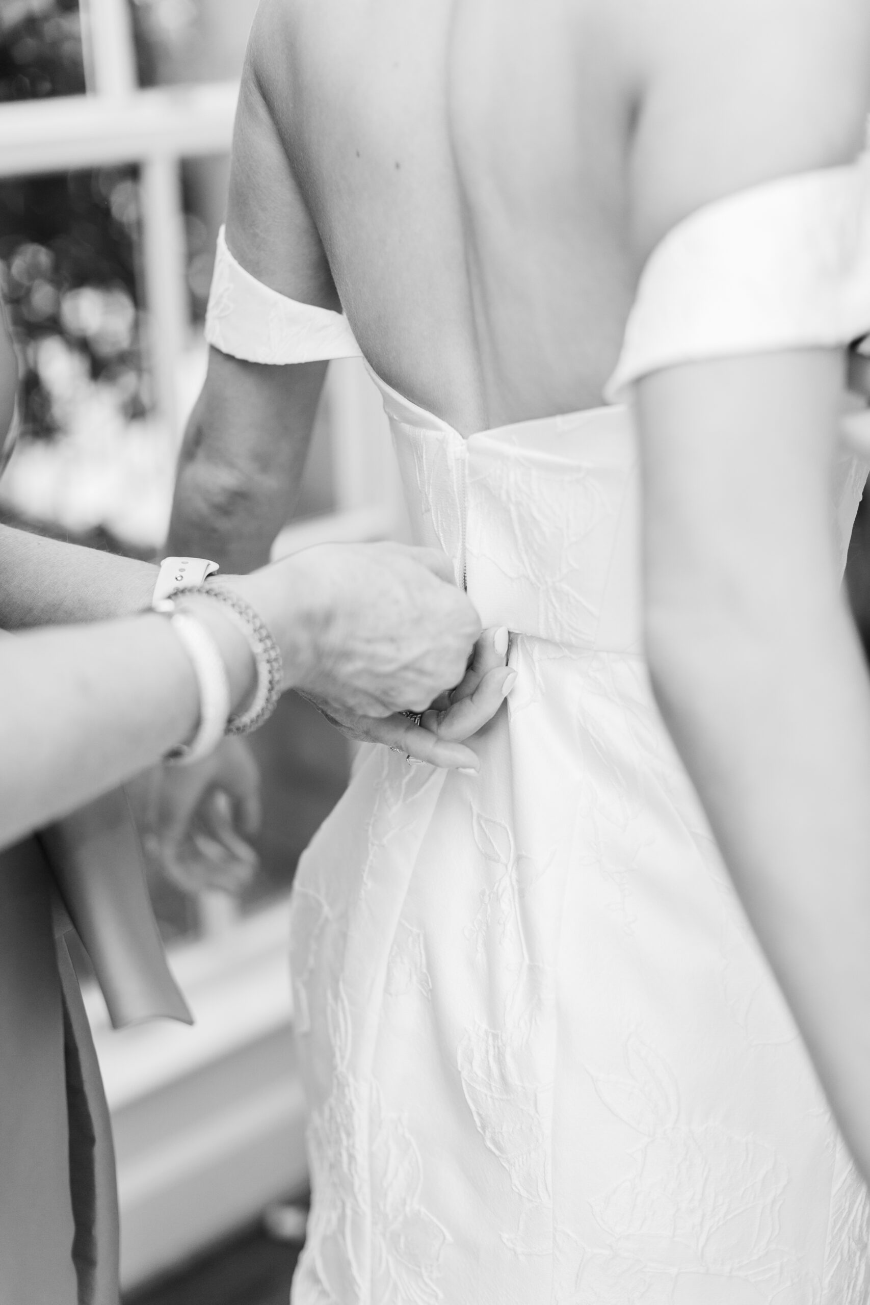 The mother of the bride zips up the wedding dress.