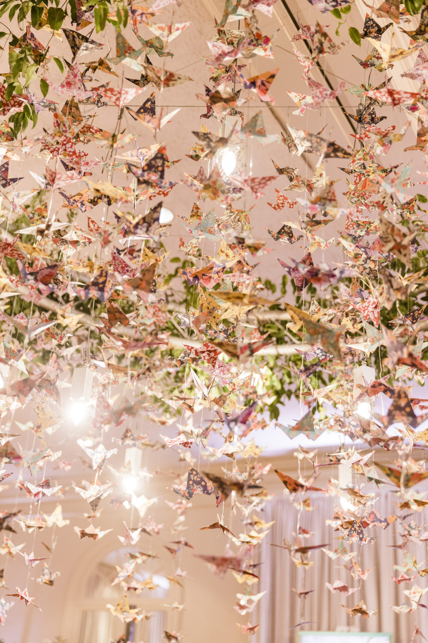 Origami cranes are suspended as a chandelier for the wedding reception.