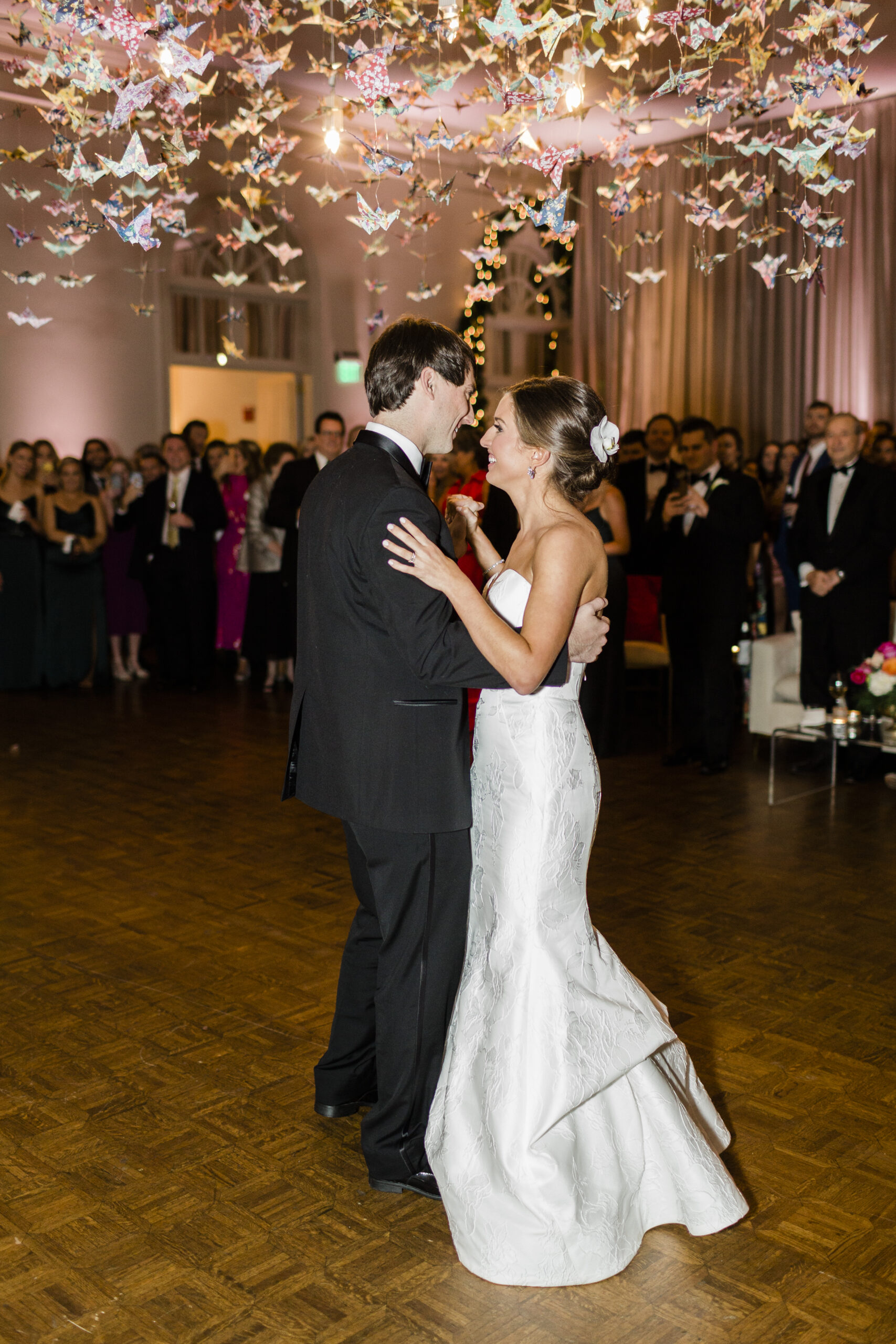 The bride and groom share their first dance under a custom origami chandelier.