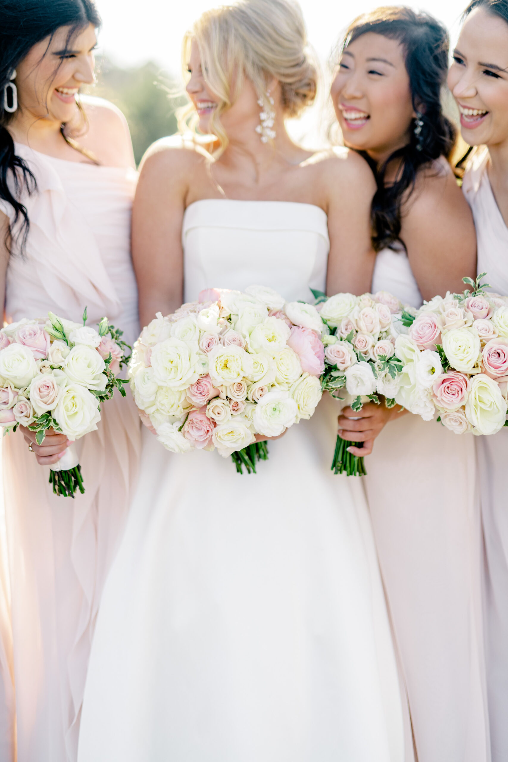 The bride and bridesmaids smile with their bouquets for the spring wedding at Marsgate.