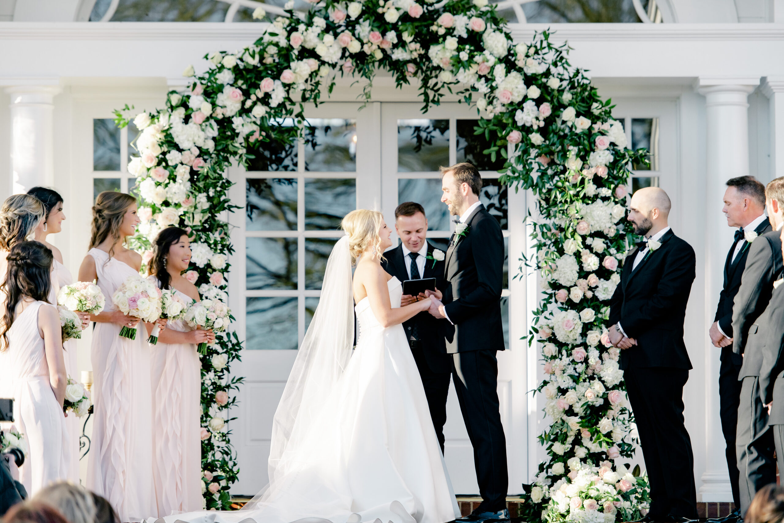 The bride and groom hold hands during their ceremony in front of Marsgate wedding venue in Alabama.