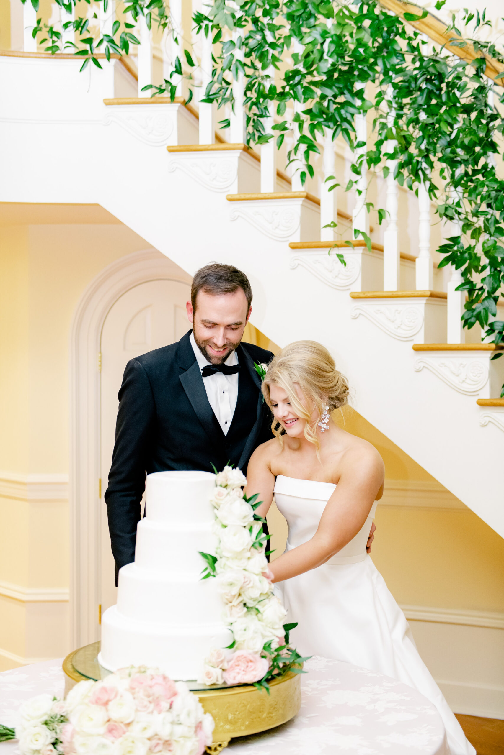 The bride and groom cut the cake in front of the staircase at Marsgate in Alabama.