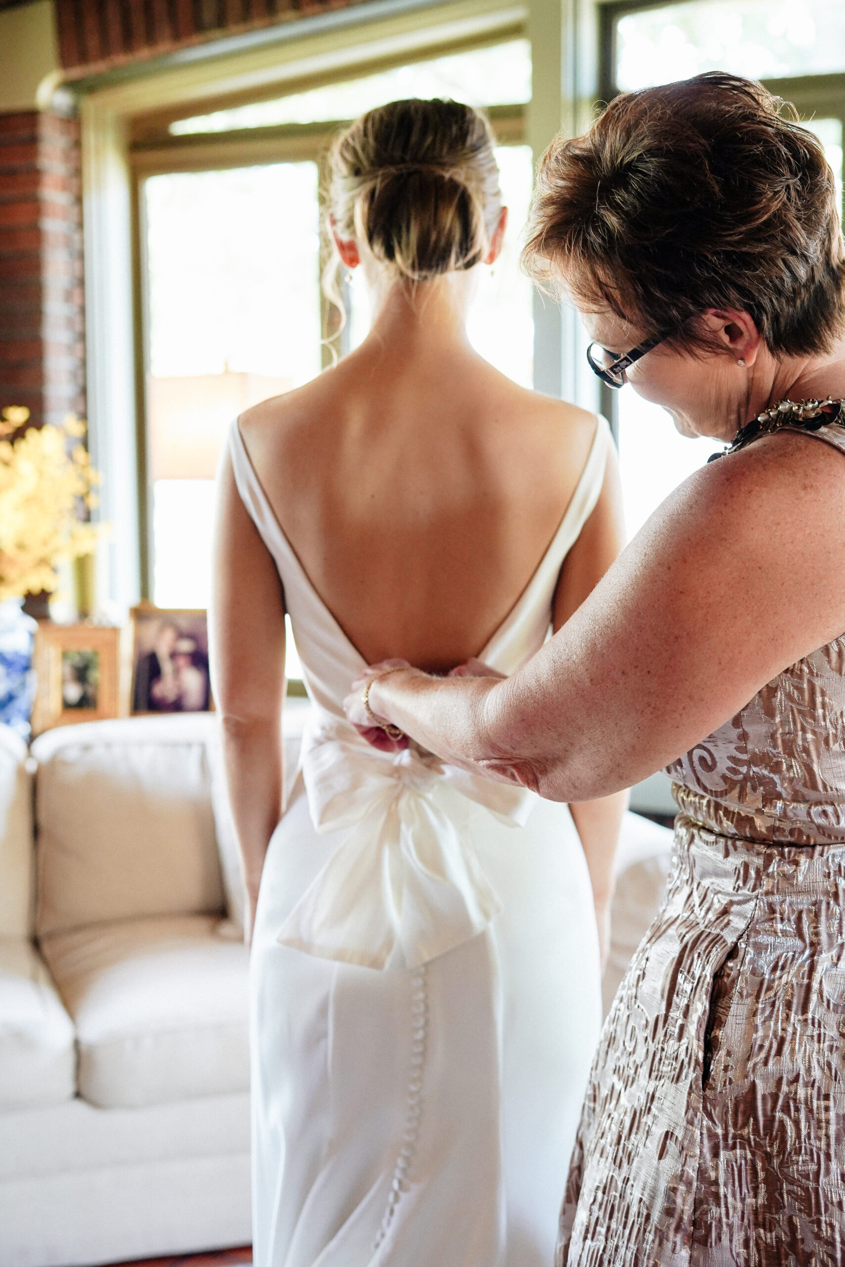 The mother of the bride helps her daughter into her wedding dress.