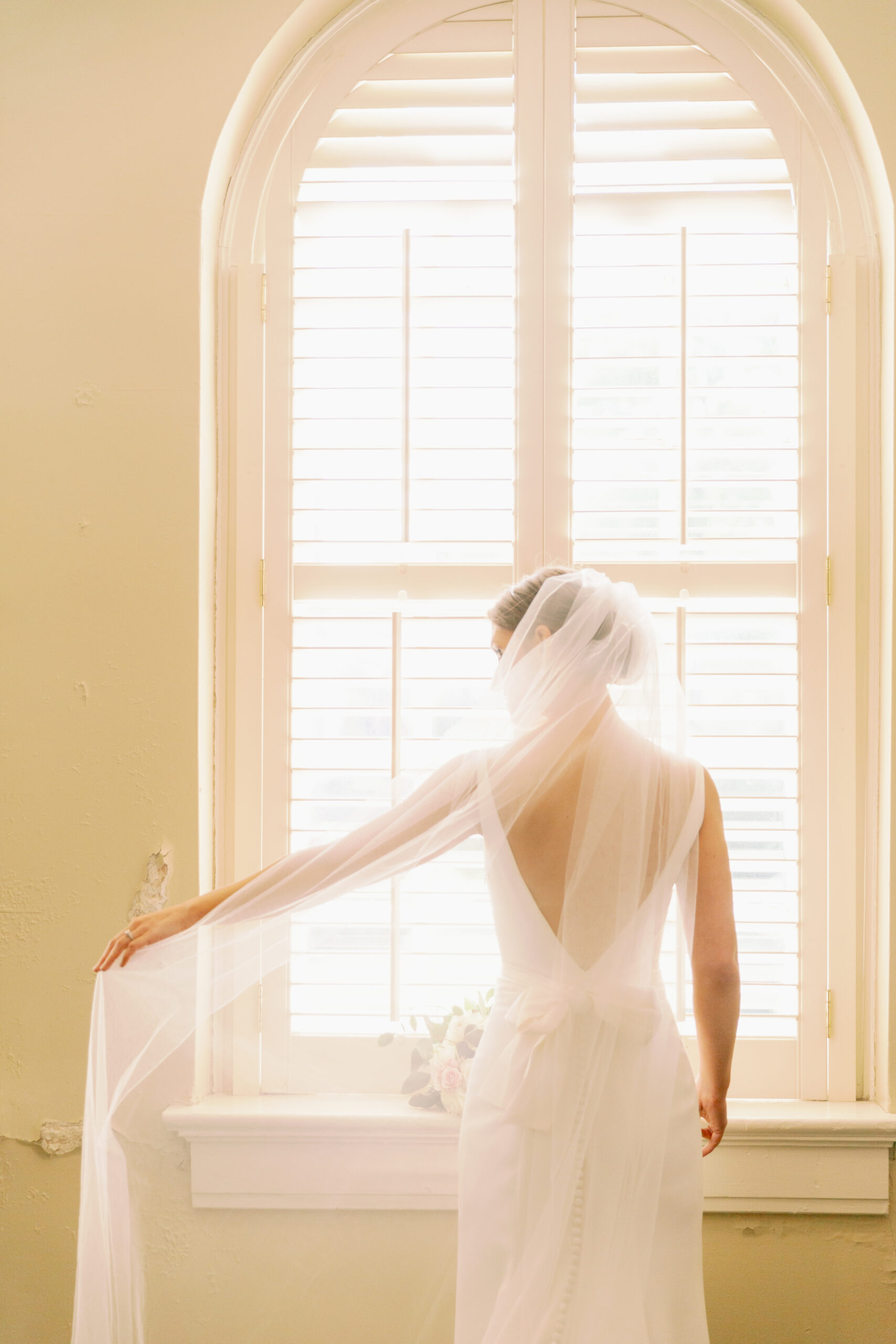 The bride holds her veil before her Alabama wedding.