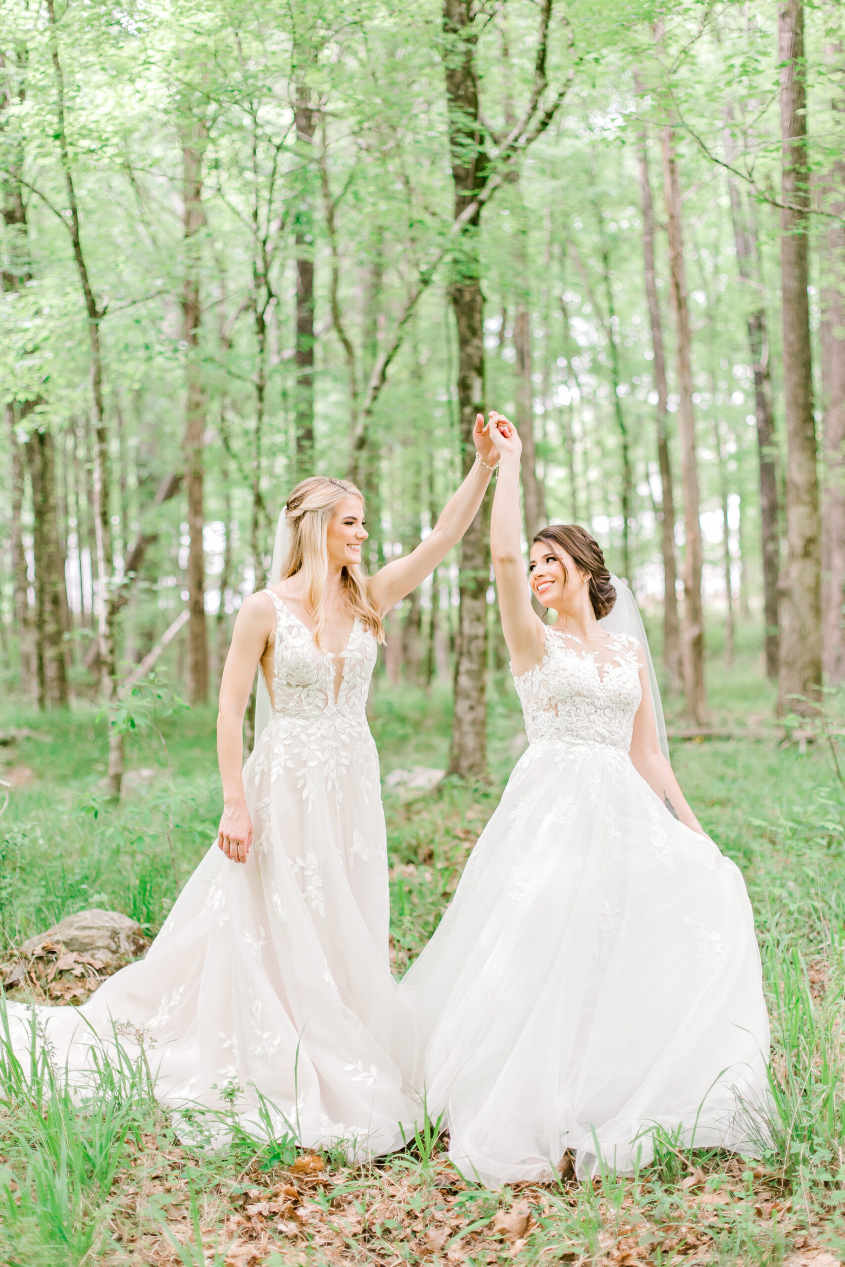 The brides hold hands in the woods in Alabama.