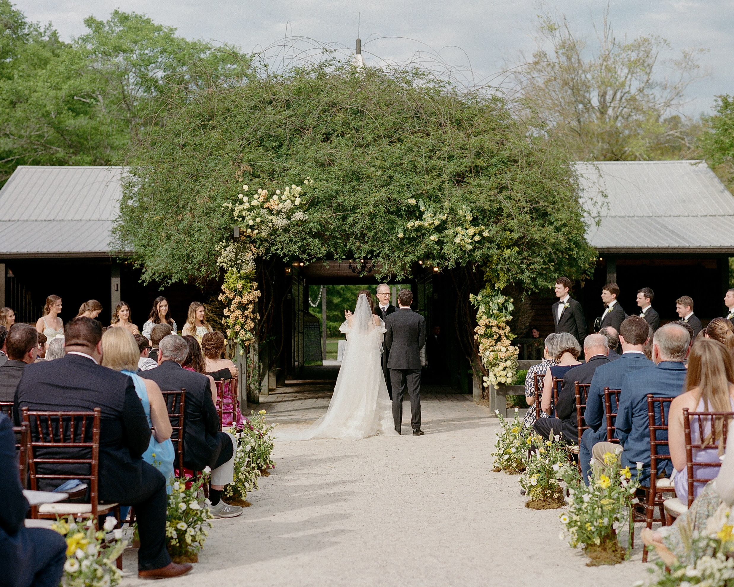 The bride and groom stand in front of the wedding ceremony at Windwood Equestrian.