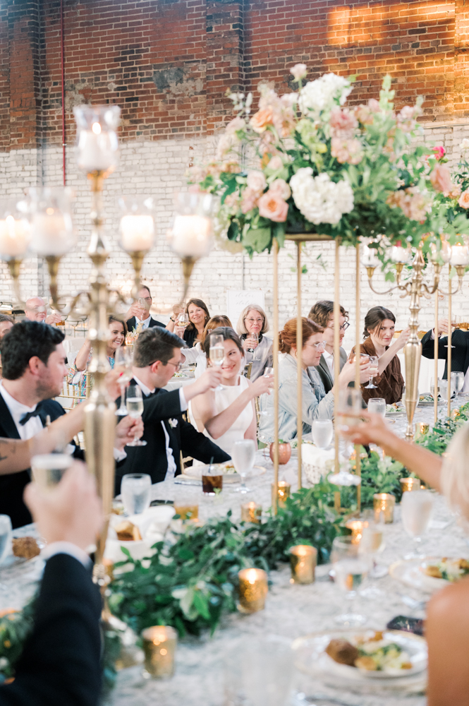 The reception guests raise their glasses for a toast at the Southern wedding.