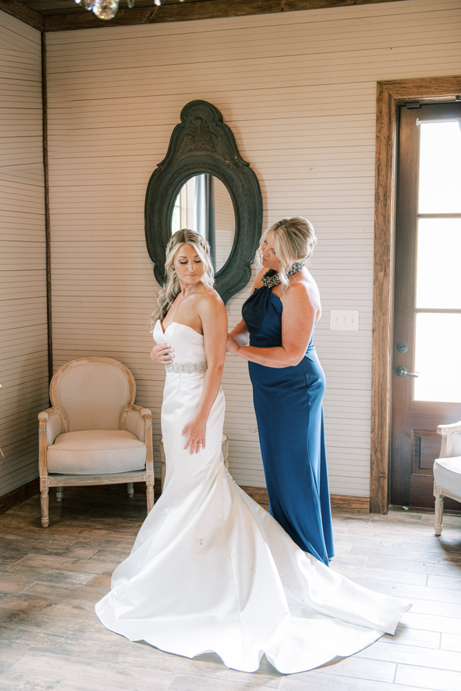 The mother of the bride helps her daughter into her wedding dress before the ceremony.