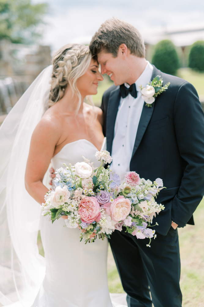 The bride holds her pastel wedding bouquet next to the groom before their Southern wedding ceremony.