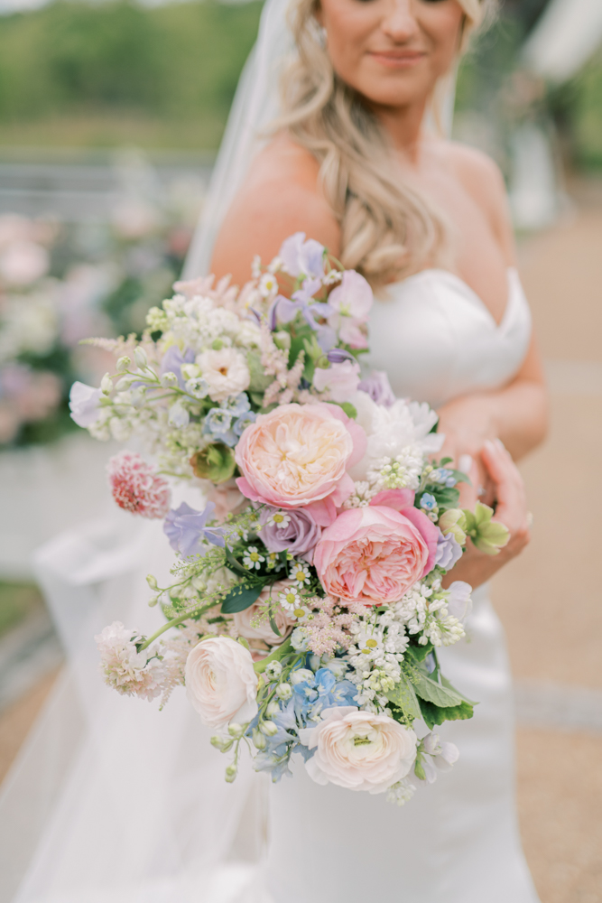 The bride holds a pastel bouquet of flowers for her spring wedding in Alabama.