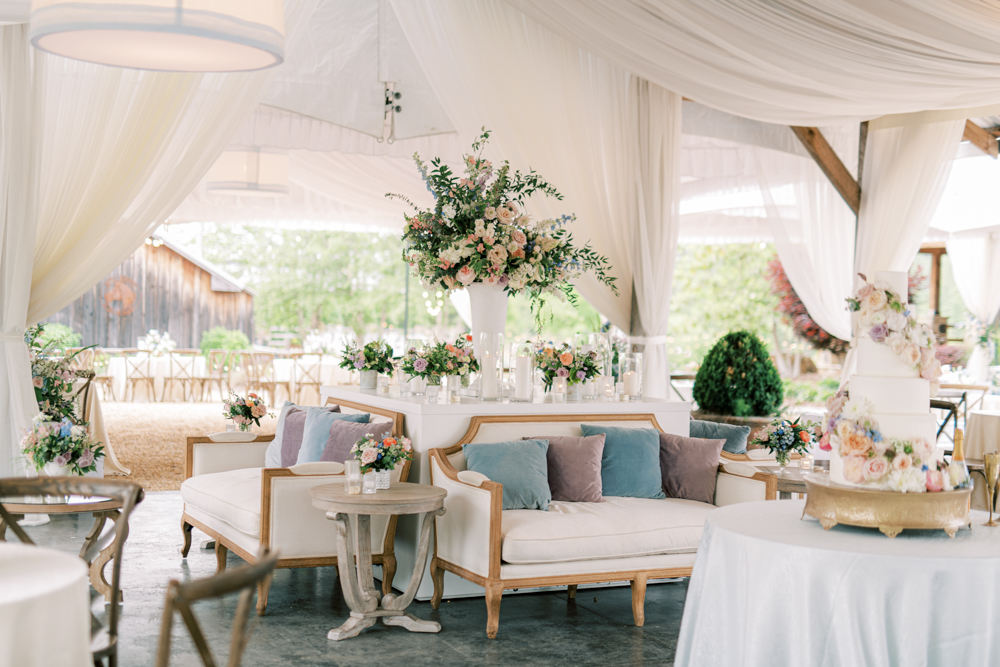 The Southern wedding reception has lounge furniture and pastel flowers at Otter Creek Farmstead.