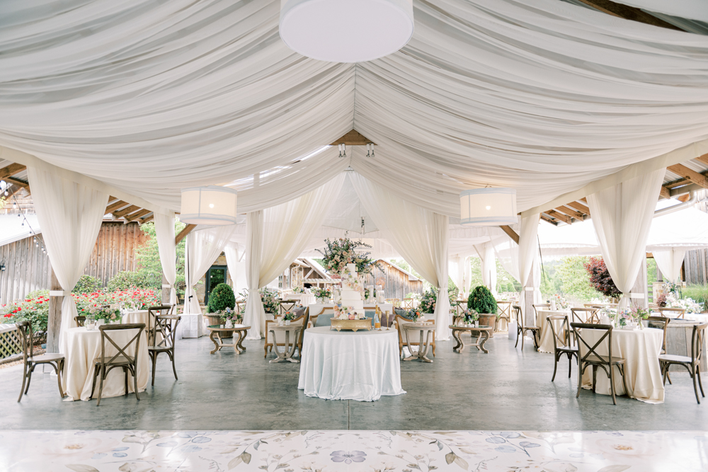 The wedding reception is decorated with pastel flowers and drapery at Otter Creek Farmstead.