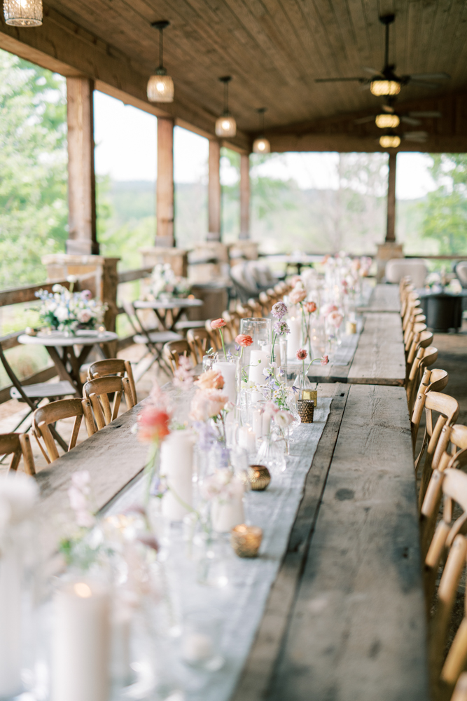 Farm tables are decorated with flowers and candles for the wedding reception at Otter Creek Farmstead in Ohatchee, Alabama.