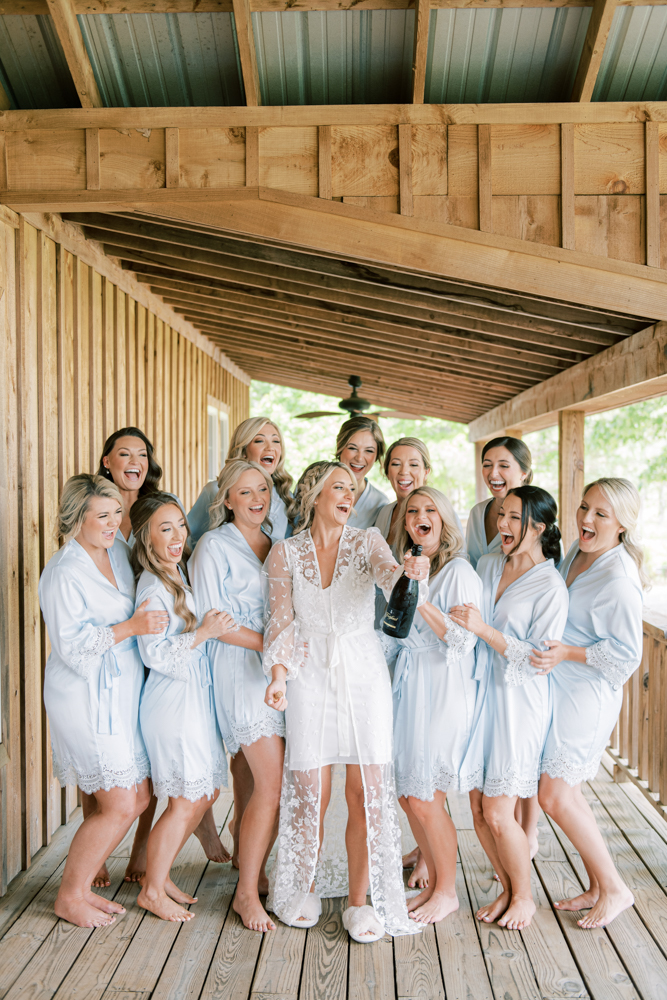 The bridal party celebrates the big day with a bottle of champagne at Otter Creek Farmstead.