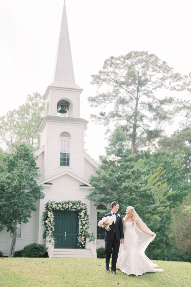 The bride and groom walk together outside the wedding chapel at Children's Harbor in Alabama.