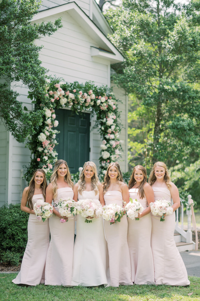 The bridesmaids stand with the bride outside the chapel at Children's Harbor in Alabama.