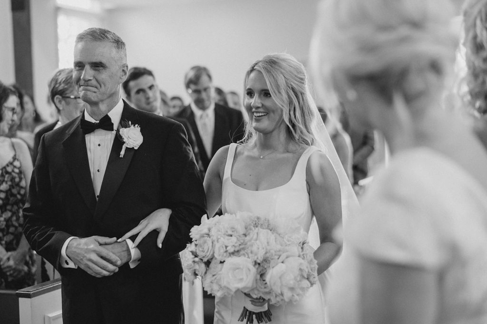 The father of the bride walks his daughter down the aisle for the wedding ceremony in Alabama.