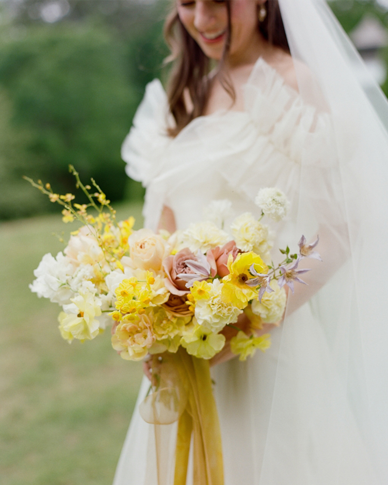 The bride holds a bright, yellow bouquet with matching ribbons for her Southern wedding.