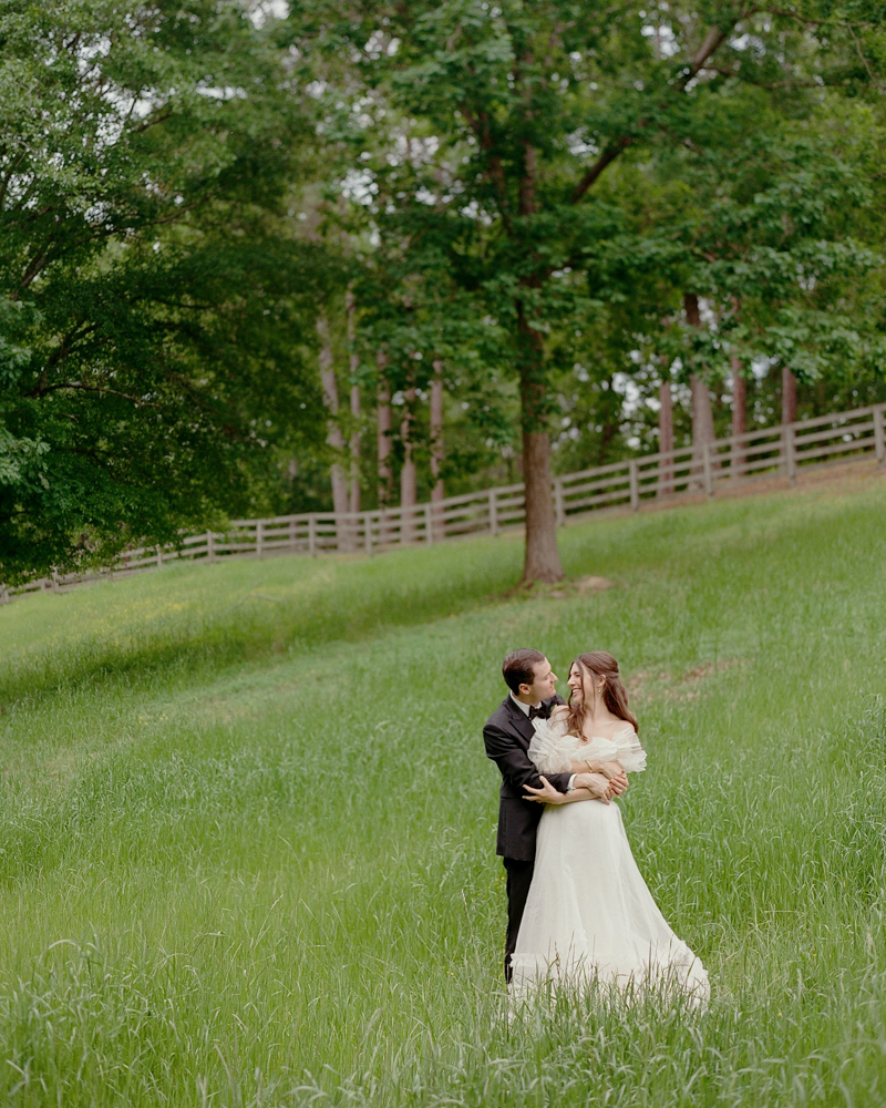 The bride and groom embrace in the field before their Southern wedding in Alabama.