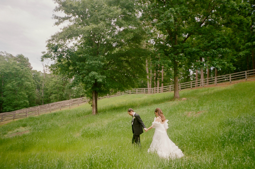 The bride and groom walk through the grass together at Windwood Equestrian wedding venue in Birmingham.